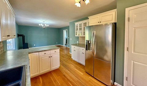 A kitchen with a stainless steel refrigerator and wooden floors.