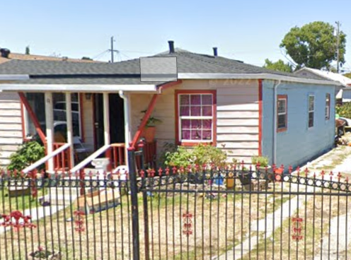A small house with a red door and a black fence.