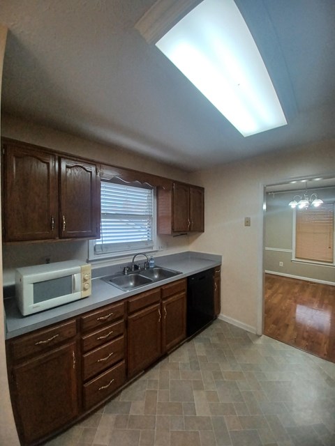 A kitchen with brown cabinets and a white microwave.
