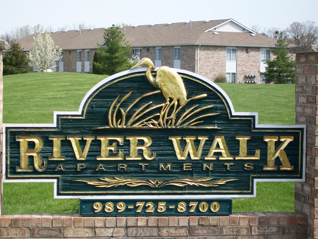 A sign for River Walk Apartments with a phone number on it.