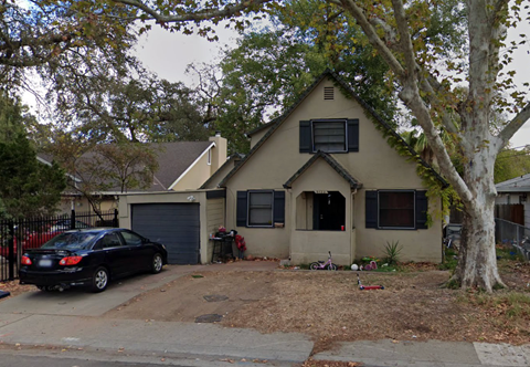 A black car is parked in front of a house.