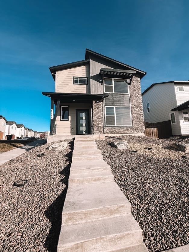 A modern house with a grey front yard and a stone pathway leading to the entrance.
