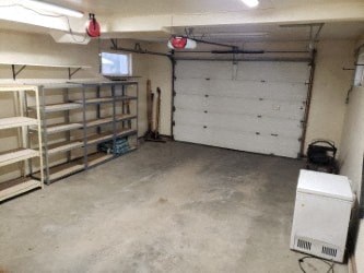 A white garage with a white door and a white cabinet.