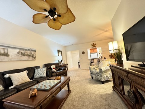 A living room with a ceiling fan and a painting on the wall.