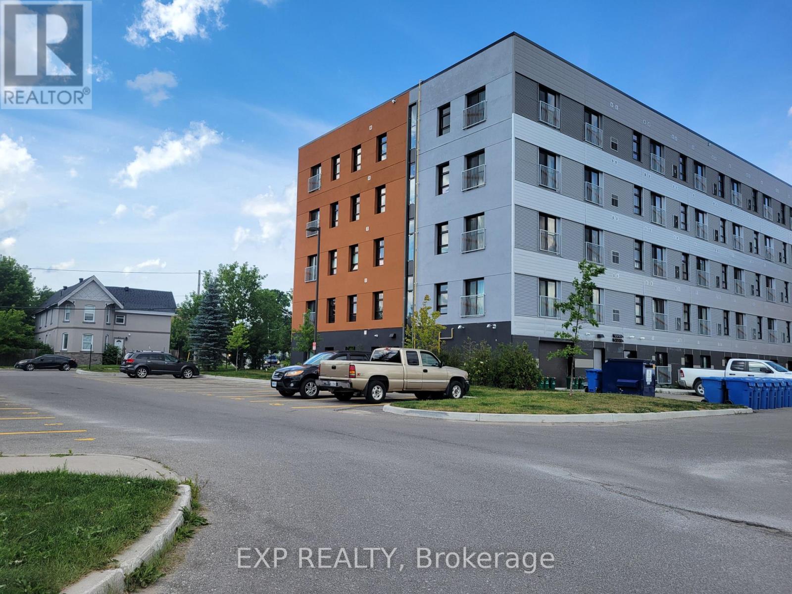 A parking lot with a white truck and a black car in front of a building with the words EXP REALTY, Brokerage on it.