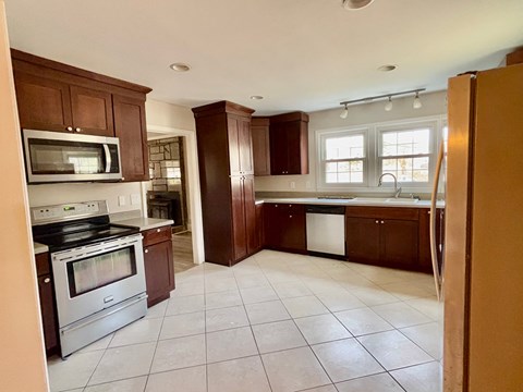 A kitchen with brown cabinets and white appliances.