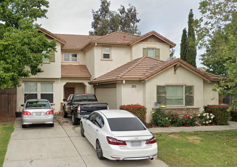 A white car is parked in front of a house.