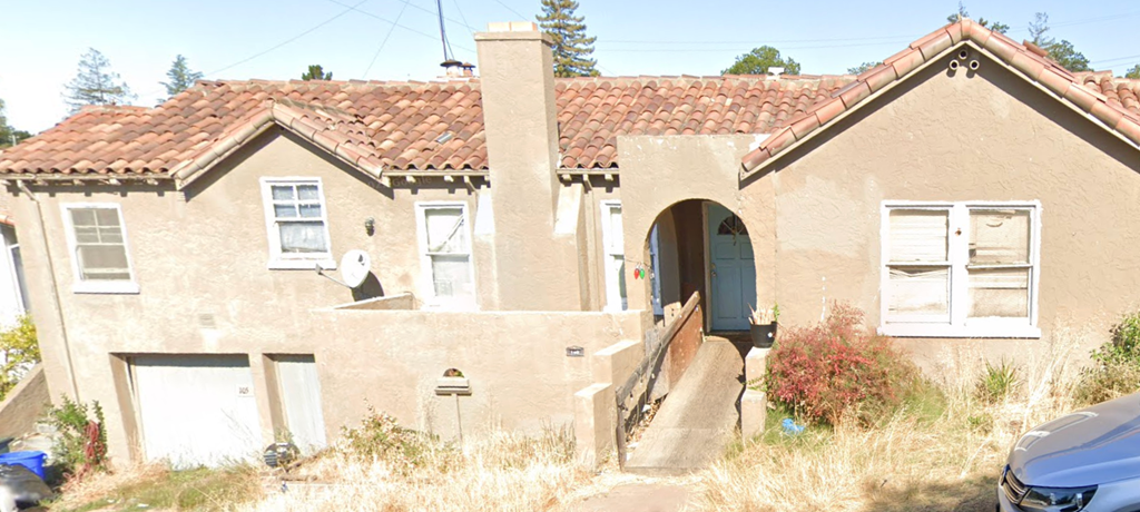 A house with a red tile roof and a blue car parked in front.