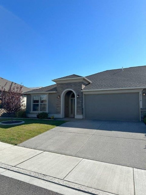 A house with a grey garage door and a brown roof.