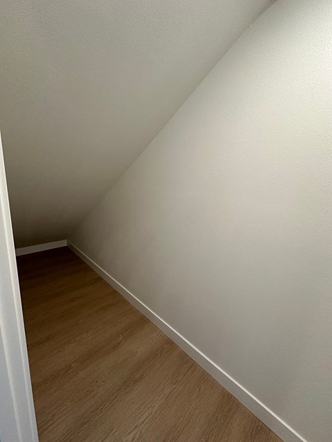 A corner of a room with wooden flooring.