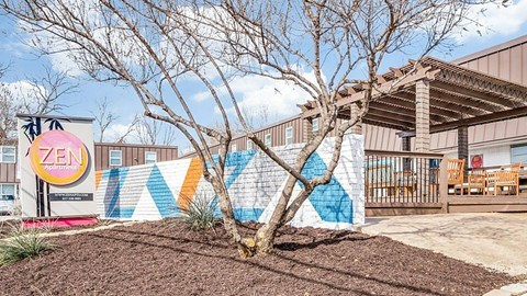 A tree in front of a building with a mural on the wall.