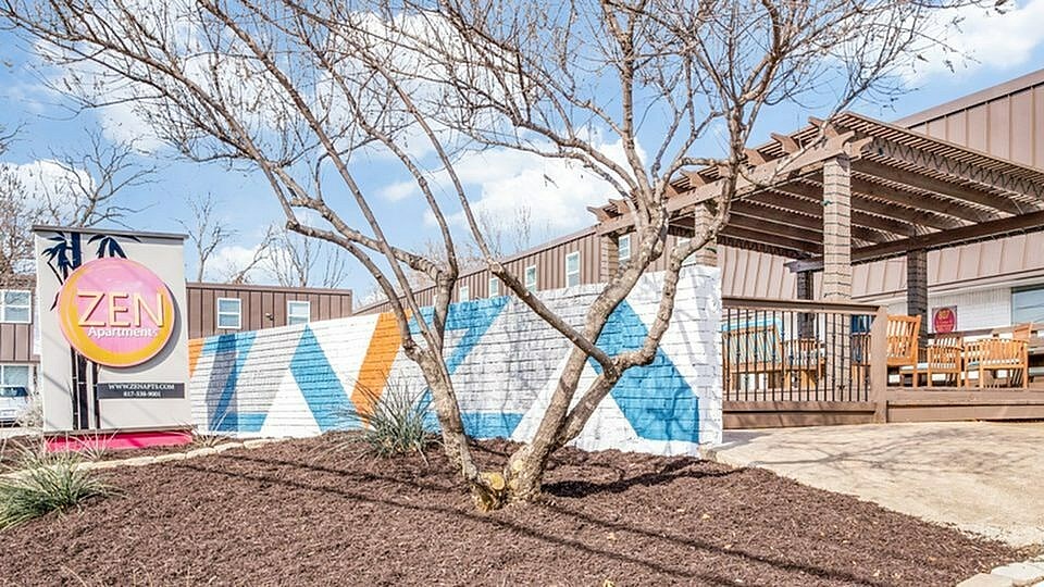 A tree in front of a building with a mural on the wall.