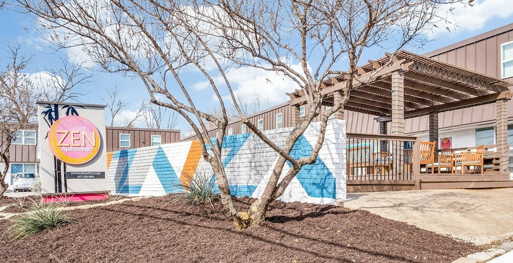 A tree in front of a Zen sign and a mural.