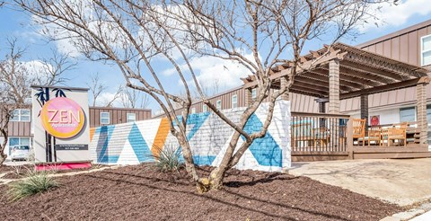 A tree in front of a Zen sign and a mural.