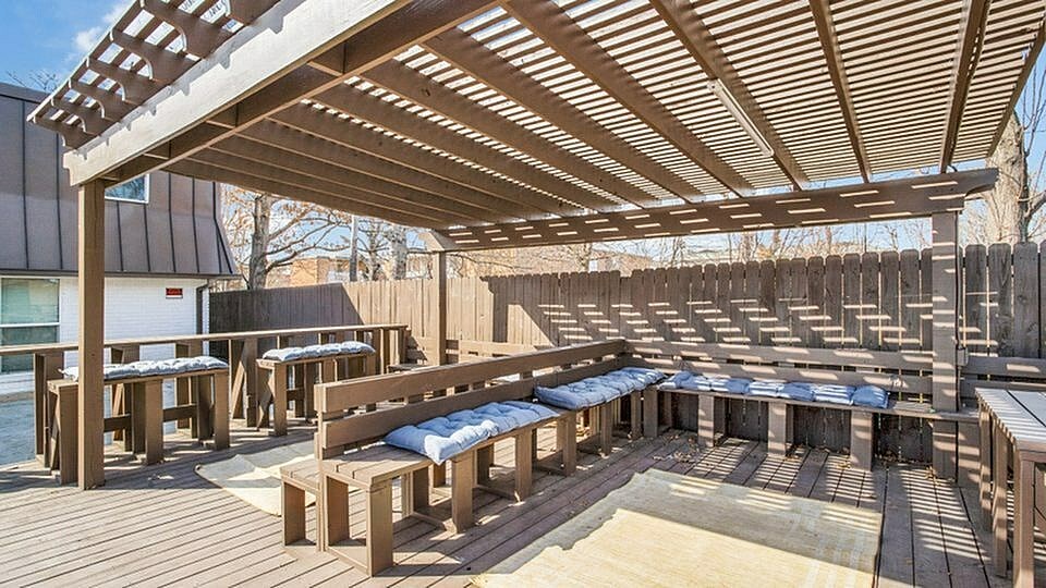 A wooden deck with a pergola and benches.