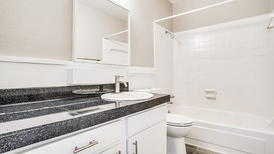 A white bathroom with a black granite counter top.
