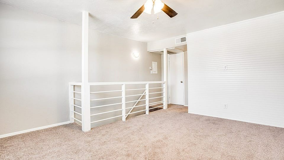 A room with a carpeted floor and a ceiling fan.