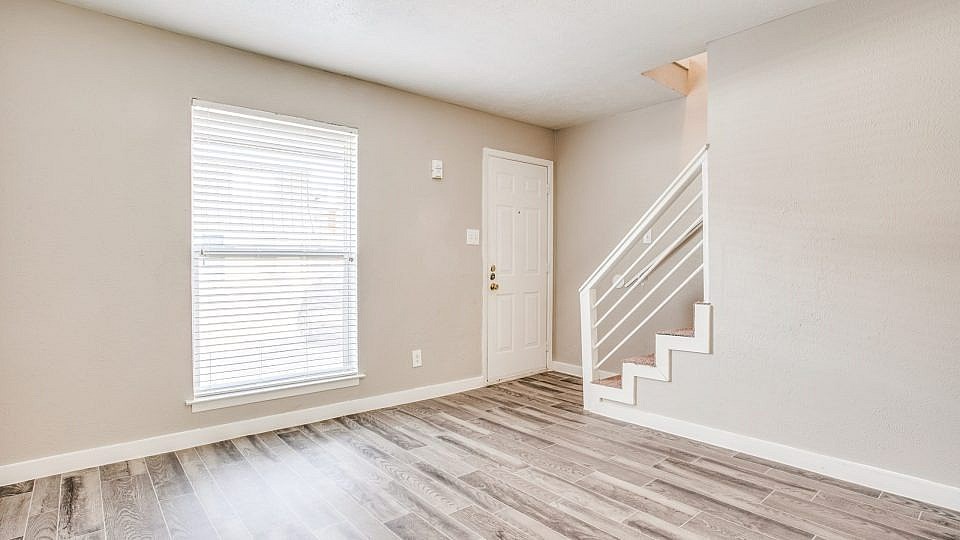 A room with a staircase and a window with blinds.