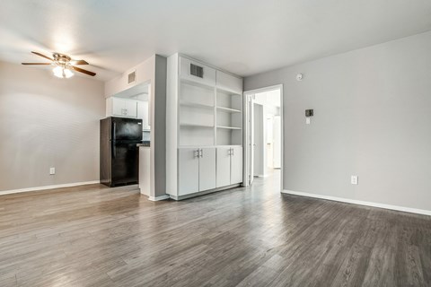 A spacious room with a ceiling fan and a black refrigerator.