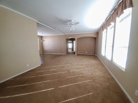 A spacious room with a carpeted floor and a ceiling fan.