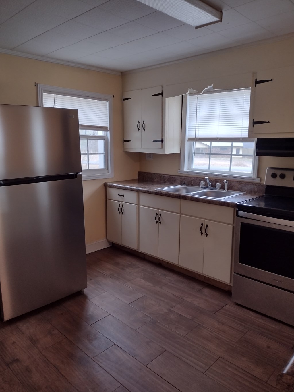 A kitchen with a refrigerator, cabinets, and a stove top oven.