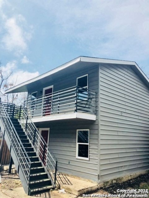 A house with a grey siding and a staircase leading to the second floor.