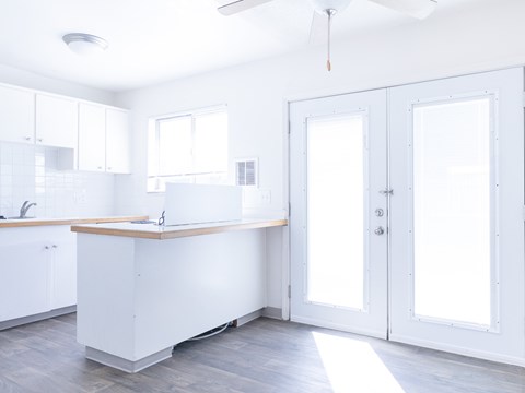 A white kitchen with a wooden countertop and a ceiling fan.
