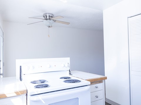 A white stove with a fan above it in a kitchen.