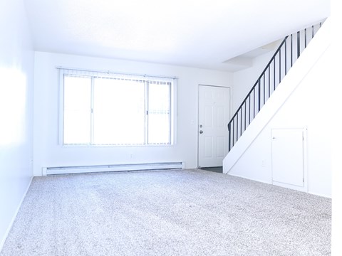 A spacious room with a staircase and a window.