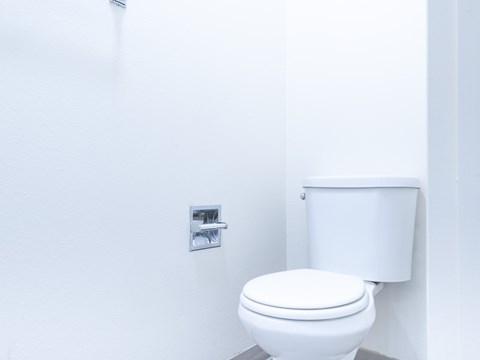 A white toilet in a bathroom with a white wall and a white towel rack.