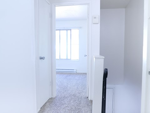 A white door is open to a room with a carpeted floor.