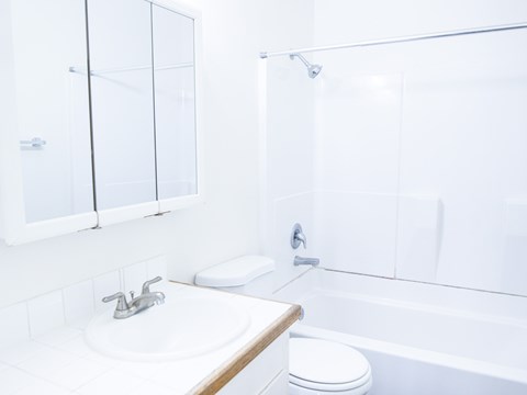 A white bathroom with a toilet, sink, and bathtub.