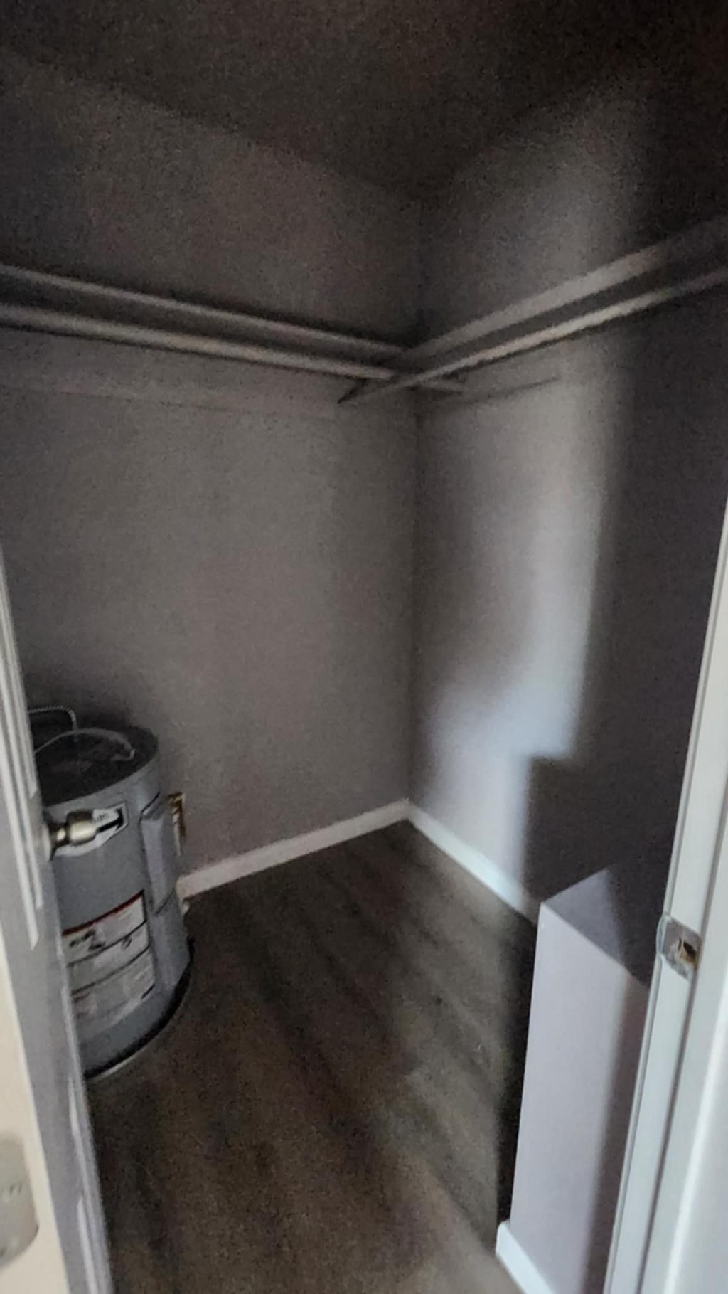 A small, empty room with a trash can and a white door.