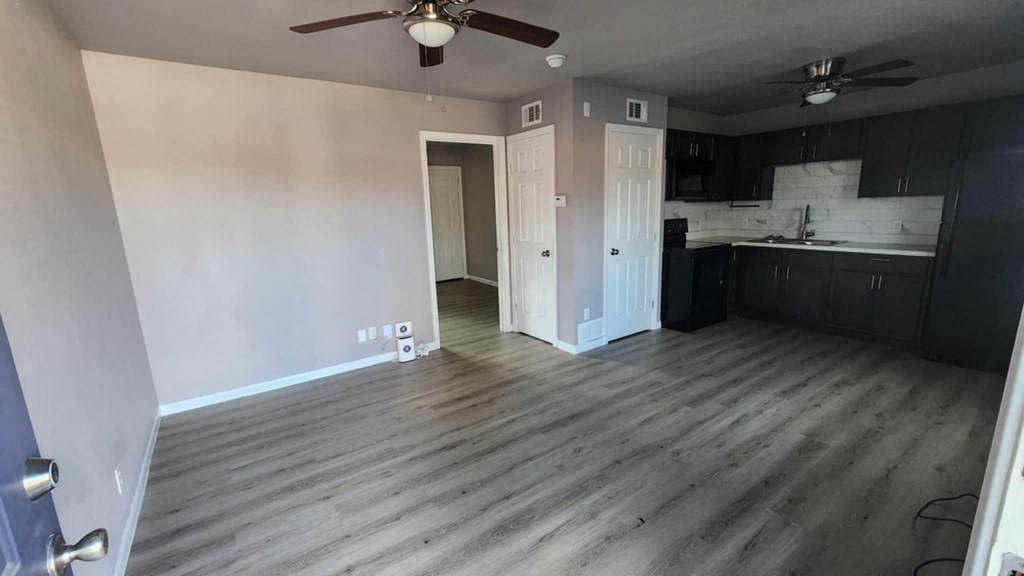 A room with a ceiling fan and a doorway leading to another room.