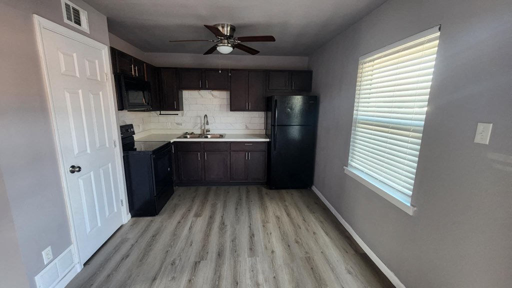 A kitchen with a black refrigerator and a white door.