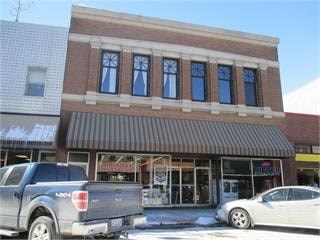 A silver truck is parked in front of a building with a brown awning.