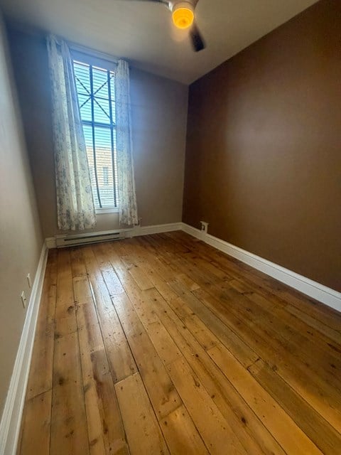 A room with wooden flooring and a window with a curtain.