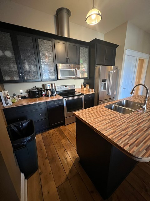 A kitchen with black cabinets and a wooden counter top.