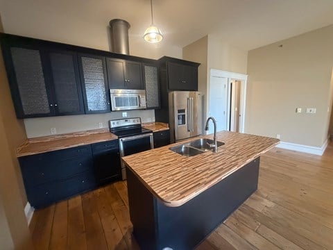 A kitchen with black cabinets and a wooden countertop.