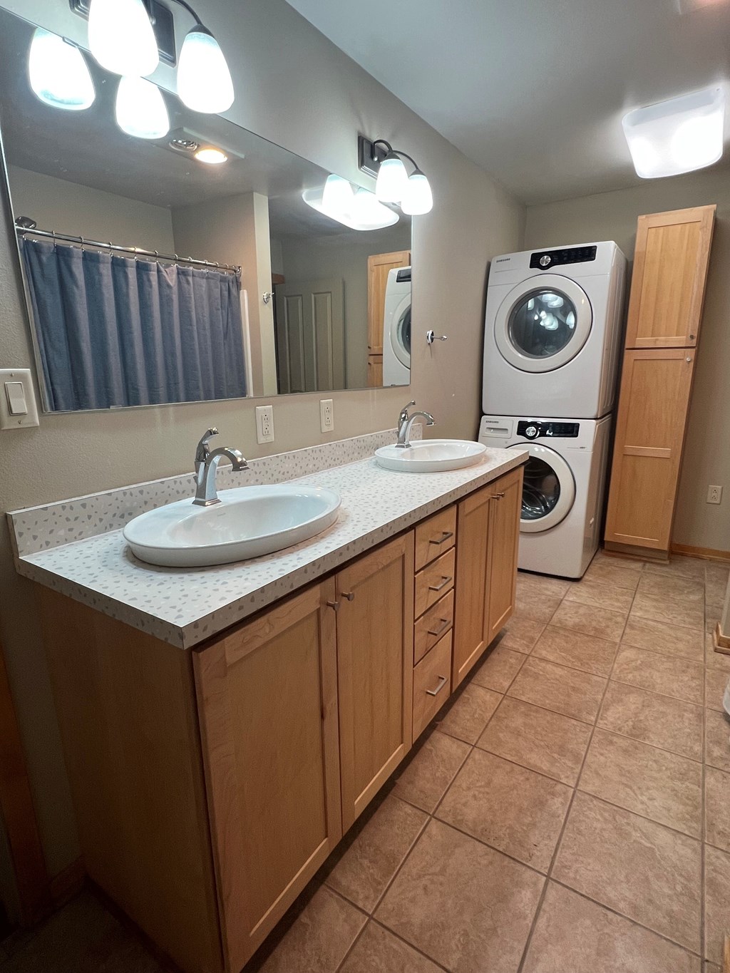 A bathroom with a double sink and a washer and dryer.