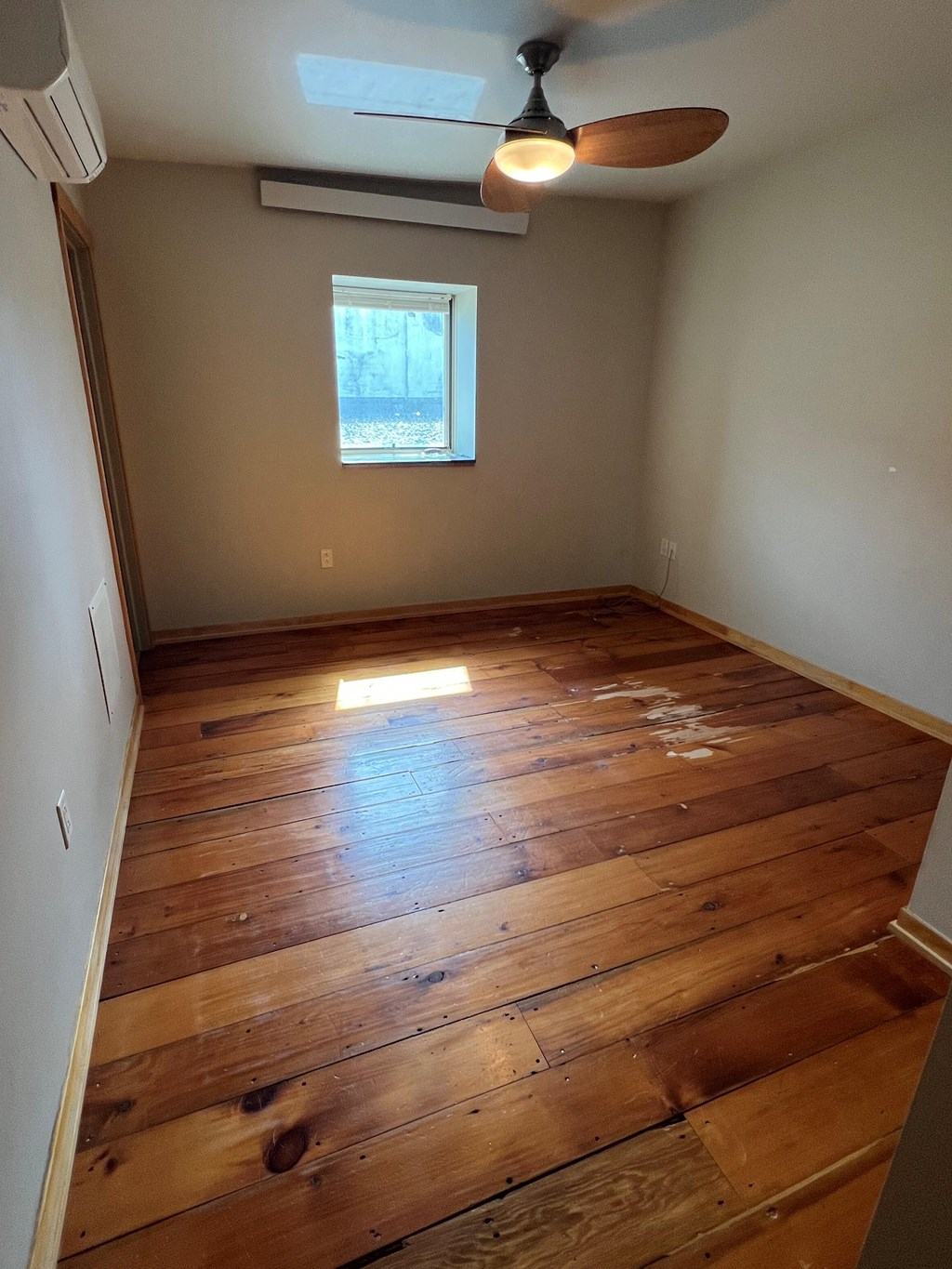 A room with wooden floors and a ceiling fan.