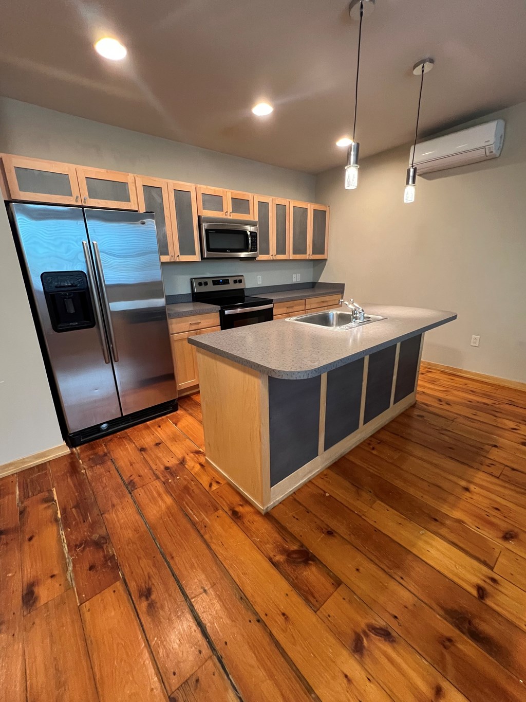 A kitchen with wooden floors and a refrigerator.