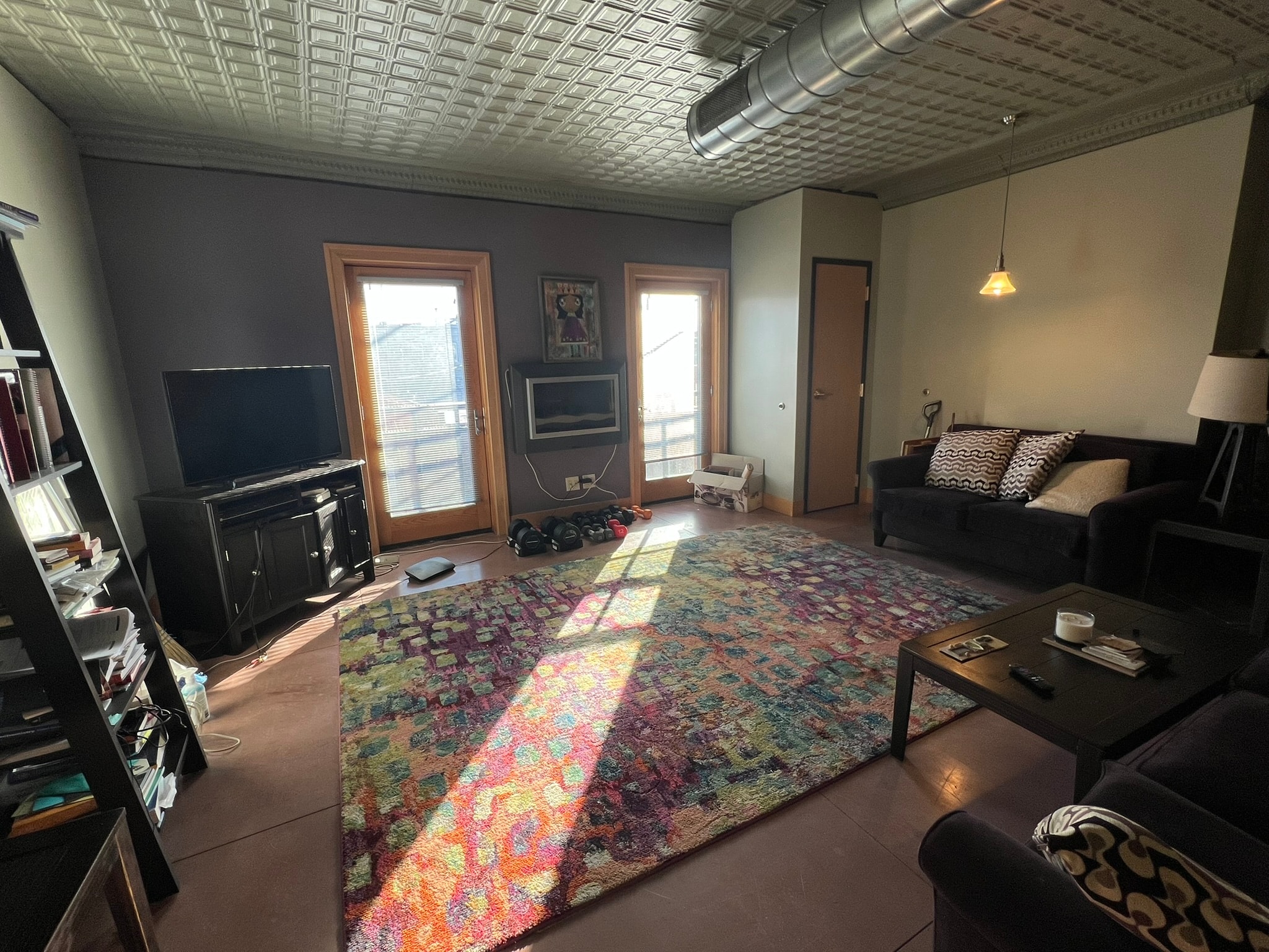 A living room with a couch, a rug, and a television.