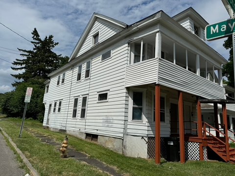 A two-story house with a porch and a fire hydrant in front.