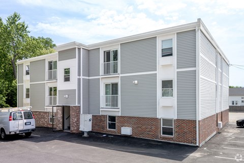 A white van is parked in front of a two-story apartment building.