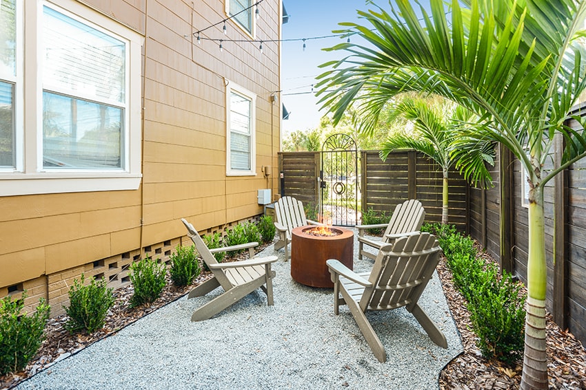 A patio with a fire pit and chairs.