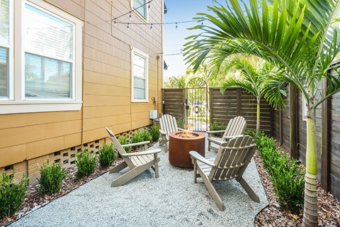 A patio with a fire pit and chairs.