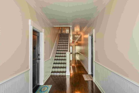 A hallway with a staircase and a chandelier.
