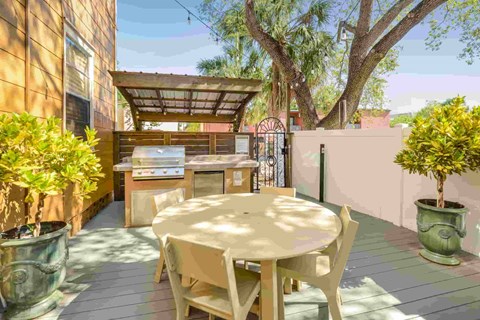 A patio with a table and chairs is surrounded by potted plants.