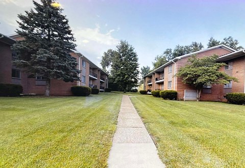 A long concrete walkway leads between two rows of apartment buildings.